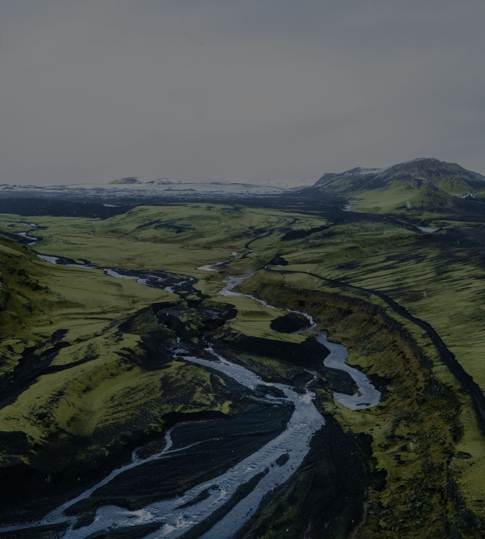 Um rio glacial se ramificando por um vale verde, visto do alto